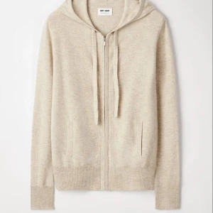 Beige hoodie i kashmir från Soft Goat - Mysig beige hoodie från Soft Goat i lyxig kashmir. Tröjan har dragkedja framtill, huva med snörning och ribbade muddar. Perfekt för en chill och stilren look. 