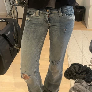 Ljusblå slitna jeans från Cheap Monday - Säljer ett par ljusblå jeans från Cheap Monday med slitningar och hål på knäna. Jeansen har låg midja, raka ben och klassisk femficksdesign. Perfekta för dig som gillar en avslappnad och edgy stil.