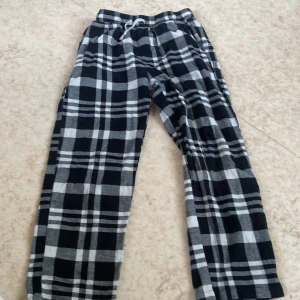 Svarta rutiga mjukisbyxor Lindex 134/140 - Mysiga mjukisbyxor från Lindex i svartvitt rutigt mönster. Byxorna har resår och snörning i midjan för extra komfort. Perfekta för chill dagar hemma eller när du vill vara extra bekväm.