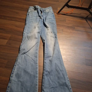 Bootcut jeans i ljusblå denim Peach XS - Bootcut jeans från Peach i ljusblå denim. Klassisk femficksmodell med knytband i midjan. Tillverkade i en mix av bomull, polyester och lite lycra för extra stretch. Perfekta för dig som gillar en avslappnad och trendig look.