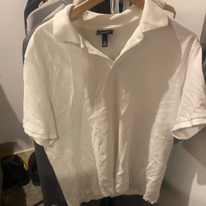 Vit pikétröja från H&M, storlek L - Klassisk vit pikétröja från H&M i regular fit. Tröjan har korta ärmar, krage och knäppning vid halsen. Perfekt basic-plagg i bomull som funkar året runt och är lätt att matcha med jeans eller shorts.