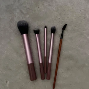 Set med sminkborstar  - Säljer ett set med fem sminkborstar var av frys i rosa/lilla fluffiga borstar samt en ögonbrynsborste. Perfekt för applicering av puder, ögonskugga och bryn. Alla borstarna är oanvända 💗