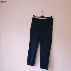 Mörkblå byxor Holly & Whyte Lindex strl 40 - Mörkblå byxor från Holly & Whyte by Lindex i storlek 40. Byxorna har en snygg guldfärgad dragkedja i sidan och är raka i modellen med croppad längd. Perfekta till en stilren look och enkla att matcha med olika toppar. Helt & fint skick dock lite ljusare i färgen