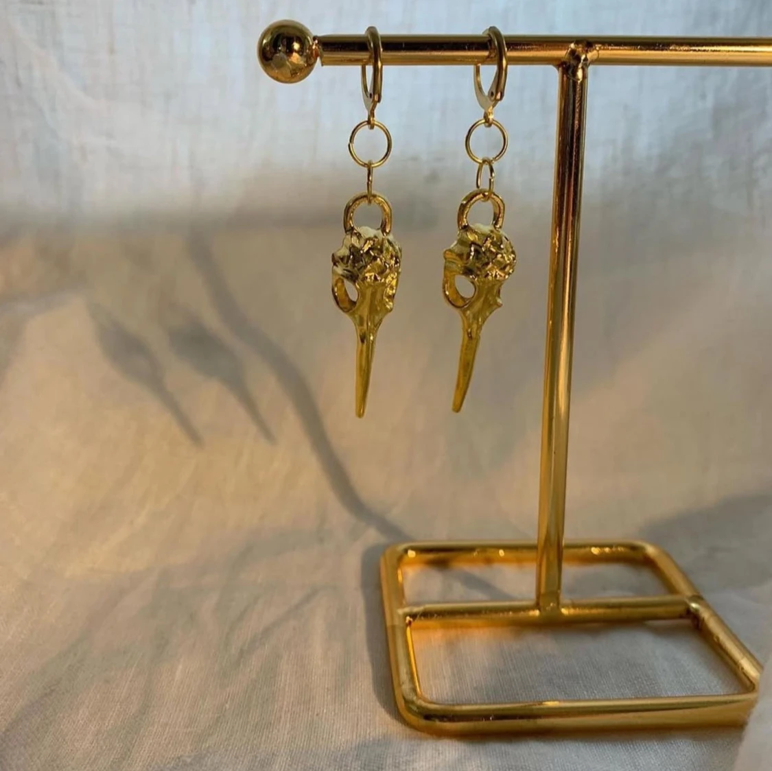 Guldiga örhängen med fågelskalle