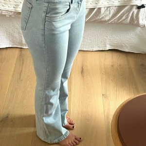 Lågmidjade ljusa jeans  - Säljer ett par ljusblå jeans med bootcut och låg midja. Dom stängs med två knappar och dragkedja. Så Snygg passform som sitter tajt upptill och släpper vid benen. Väldigt bra stretch i också så passar xs-s/m. Jag är 165cm lång