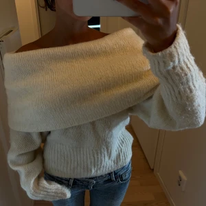 Offshoulder stickad vit tröja - Superfin offshoulder stickad tröja i vit färg. Tröjan har bred krage som vilar över axlarna och långa ärmar med ribbade muddar. Perfekt för dig som vill ha en mysig men ändå snygg look till höst och vinter 🩷
