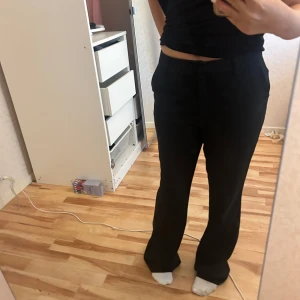Svarta kostymbyxor  - Snygga svarta kostymbyxor i bootcut-modell med midwaist. Byxorna har en klassisk look med utsvängda ben och passar perfekt till en stilren outfit. Materialet känns mjukt och följsamt, och de har fickor i sidorna. Perfekta för dig som gillar en clean och modern vibe. Säljer pågrund av att de inte används och prislappen finns kvar. Hör av er vid intresse!