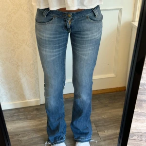 Lågmidjade utsvängda jeans - Skit snygga jeans från Lee! Storleken är W27 L31, passar xs-s. Uppsprättade där nere men blir en cool detalj! Kom privat för mått och frågor🥰