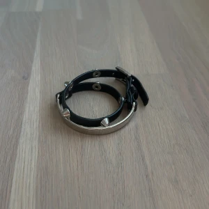 Svart bälte med silverfärgade nitar - Coolt svart bälte i skinn med silverfärgade konformade nitar runtom. Smal modell som passar perfekt till jeans eller för att ge outfiten en edgy touch. Spännet är också i silverfärgad metall och bältet har flera hål för justering.
