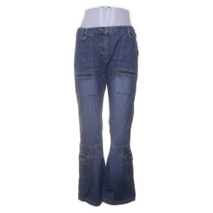 Blå cargojeans med bootcut - Snygga blå cargojeans med flera fickor och bootcut-ben. Jeansen har låg midja och är tillverkade i klassiskt denimtyg. Perfekta för dig som gillar en avslappnad och trendig stil med extra detaljer.