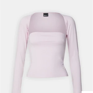Ljusrosa långärmad topp Gina Tricot - Supersöt ljusrosa långärmad topp från Gina Tricot. Modellen är croppad med en snygg, rak halsringning och figurnära passform. Tillverkad i mjukt och stretchigt material som sitter bekvämt. Perfekt att styla med jeans eller kjol för en trendig look.