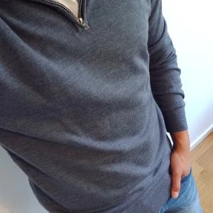 Grå stickad half zip-tröja i merinoull, pris kan diskuteras - Snygg grå stickad tröja med half zip och hög krage. Tröjan har lång ärm, ribbade muddar och är i mjukt material som passar perfekt till jeans eller chinos. Enkel och stilren design som funkar året runt. Knappt använd och pris går att diskuteras!