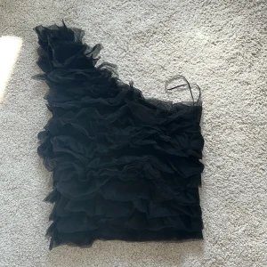 Svart oneshoulder volangtop från MQ - Säljer en svart oneshoulder topp från MQ i storlek XS💕💕