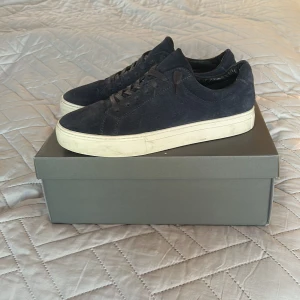 Mörkblå sneakers från Vagabond - Snygga mörkblå sneakers från Vagabond med klassisk rund tå och platt vit sula. Skorna är gjorda i mocka och har snörning framtill. Perfekta för dig som gillar stilrena och tidlösa sneakers med en modern touch.