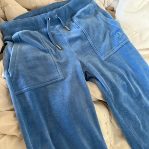 Blå Juicy Couture byxor storlek XS ❣️❣️ - Blå mjukisbyxor från Juicy Couture i velour med bred resår och snörning i midjan. Byxorna har raka ben, stora fickor fram och en bakficka med knappar. Priset kan diskuteras 💕 