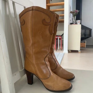 Bruna cowboy boots i skinn med klack - Snygga bruna cowboy boots med dekorativa sömmar och hög klack. Klassisk westernstil med rund tå och stilren design, perfekta för att lyfta din outfit. Köpta på vinted, jag har endast använt dom vid ett tillfälle och dom visar inte på mycket användning alls! Storlek 37 men kan både passa 36 och 37. Sista bilden visar på defekter på undersulan! Hittar inget märke heller! 