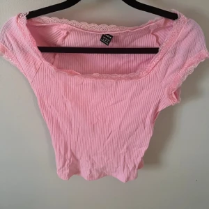 Rosa ribbad croppad topp från Shein - Söt ljusrosa croppad topp från Shein med ribbad struktur och spetsdetaljer längs halsringning och ärmslut. Aldrig använd