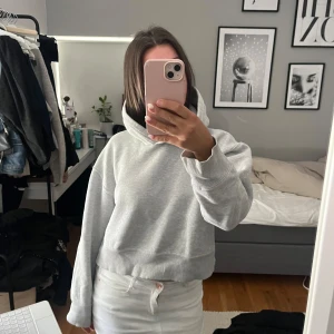 Zara hoodie  - Säljer en ljusgrå croppad hoodie med huva och långa ärmar. Tröjan har en relaxed fit och är tillverkad i mjuk bomullsmix, perfekt för chill dagar. Enkel och stilren design som passar till det mesta.