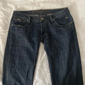 Mörkblå jeans från Cron-X med guld detaljer  - Snygga mörkblå bootcut jeans från Cron-X med guld detaljer som dragkedjor på bakfickorna och kontrastsömmar. Säljer eftersom de tyvärr inte passar mig längre. W30, Innerbenslängd 88cm. Skriv gärna om du har några funderingar💕