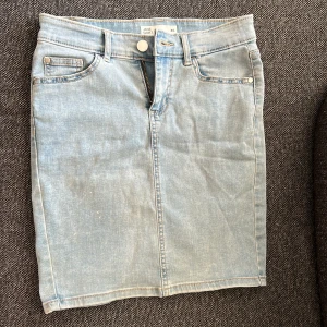 Ljusblå jeanskjol - Snygg ljusblå jeanskjol från HM i storlek XS. Kjolen har klassisk femficksdesign, bälteshällor och knapp- samt dragkedja framtill. Rak passform och slits bak för extra rörelsefrihet. 