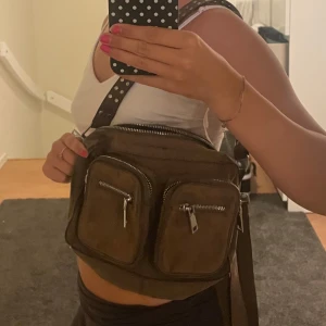 Brun axelväska i mocka från Noella - Säljer en väska från Noella som är i fint skick! Används inte längre. Nypris 799