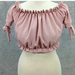 Ljusrosa croppad offshoulder topp - Superfin ljusrosa croppad topp från Nelly med offshoulder och korta ärmar med knyt. Rynkad kant upptill och nedtill ger en söt volang-effekt. Perfekt till jeans eller kjol för en chill och trendig look.