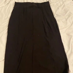 Svart ribbad långkjol från Vila - Säljer en svart långkjol från Vila i storlek L. Kjolen är ribbad och har en enkel, rak passform som sitter snyggt på kroppen. Perfekt för dig som gillar stilrena och tidlösa plagg. Materialet är mjukt och stretchigt för extra komfort.