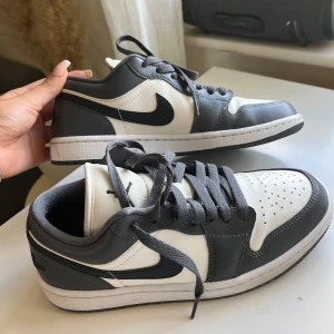 Nike Air Jordan 1 Low grå vit - Snygga Nike Air Jordan 1 Low sneakers i grå och vitt skinn med klassisk svart swoosh. 