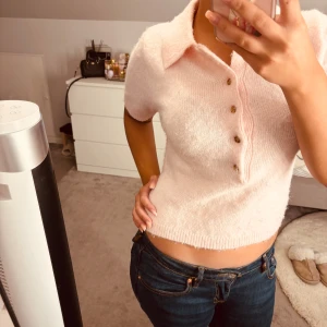 Ljusrosa stickad pikétröja Lindex - Superfin ljusrosa stickad pikétröja från Lindex med korta ärmar och klassisk krage. Tröjan har fyra snygga knappar framtill och är croppad i modellen. Perfekt för dig som gillar mjuka material och en chill, feminin stil.