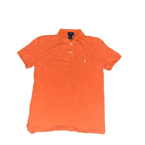 Ralph Lauren piké - Fräsch orange t-shirt från Polo Ralph Lauren med klassisk pikékrage och två knappar framtill. Ikoniska lilla broderade loggan på bröstet. Skön bomullskvalitet och korta ärmar, perfekt för chill dagar. Snygg passform och riktigt nice färg som sticker ut. Storlek 14-16 år vilket motsvarar XS men kolla måtten för säkerhetskull