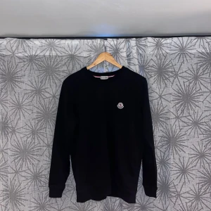 Svart Moncler tröja/sweatshirt - Säljer en svart sweatshirt från Moncler med rund halsringning och Moncler-logga på bröstet. Tröjan har långa ärmar och klassisk passform. Perfekt för dig som gillar stilrena märkesplagg. NFC finns kom dm för mer info
