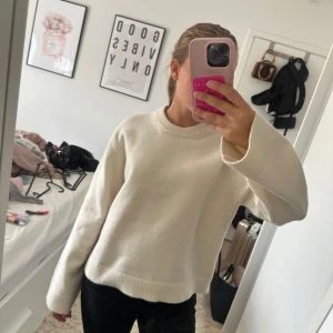 Vit stickad tröja med rund hals - Säljer en enkel och stilren vit stickad tröja med rund hals och långa ärmar. Tröjan har en loose passform och ribbade muddar vid ärmslut och nederkant. Perfekt att matcha med jeans eller svarta byxor för en clean look.