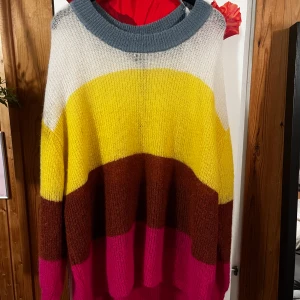Färgglad stickad tröja från Lindex - Säljer en oversized stickad tröja från Lindex i storlek XL. Tröjan har breda blockränder i blått, vitt, gult, brunt och rosa. Den har en rund halsringning och långa ärmar, perfekt för dig som gillar färg och vill ha en mysig vibe.