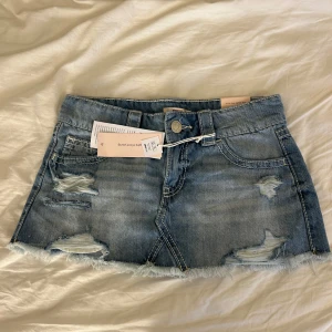 Blå jeanskjol - Säljer en helt oanvänd blå jeanskjol från Gina Tricot i storlek XS. Kjolen är kort med slitna detaljer framtill. Klassisk med snygga bakfickor och knappstängning. Perfekt för dig som gillar en söta och fina kläder. Aldrig använd och säljer för att den inte kommer till användning. ☀️