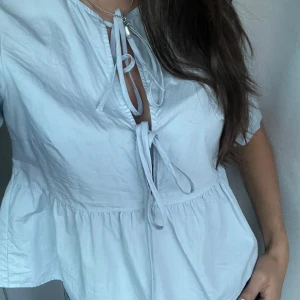 Ljusblå blus - Supersöt ljusblå blus från Hm (divided) med volang nertill och två knyt framtill. 