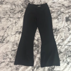 Svarta bootcut-byxor från Gina Tricot - Svarta utsvängda bootcut-byxor från Gina Tricot, modell Basically Basics. Byxorna har en hög midja och är tillverkade i ett stretchigt material som ger en bekväm passform. Perfekta för en stilren och trendig look. ENDAST ANVÄNDA 1 GÅNG!!!