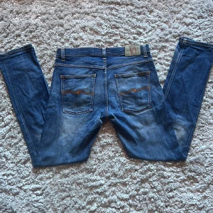 Nudie Grim Tim - Säljer dessa snygga Nudie Grim Tim jeansen i storlek 34/34. De är i okej skick med ett hål vid knät annars inga defekter. Färgen/washen är Revelation blue. Bara att skriva över frågor och funderingar.