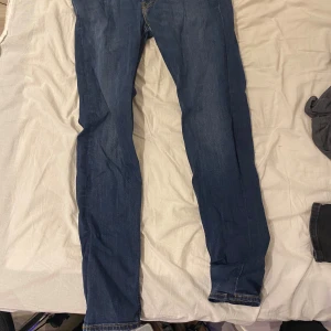 Blå jeansbyxor från Lee - Säljer ett par klassiska blå jeans från Lee med raka ben och snygga kontrastsömmar. Byxorna har fem fickor och Lee-logga på baksidan. Perfekta för dig som gillar tidlös denimstil.