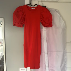 Röd klänning med puffärm från Zara - Säljer en röd kortklänning från Zara med puffärmar och rund halsringning. Klänningen är ribbad i materialet och har en figurnära passform. Aldrig använd