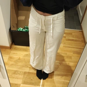 Vita linnebyxor med dragsko från H&M - Säljer ett par vita linnebyxor från H&M med dragsko i midjan och stora fickor framtill. Byxorna har en avslappnad passform och raka ben, perfekta för varmare dagar.