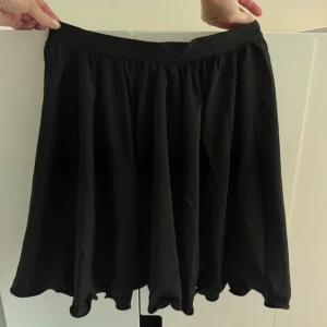 Svart kort kjol NAKD - Säljer en snygg svart kjol från NAKD i storlek M. Kjolen har en luftig och fladdrig design som passar perfekt för både vardag och fest. Kjolen har ett väldigt fint fall. Helt oanvänd med lappen kvar