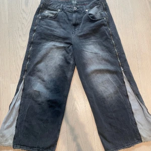 Baggy jeans med dragkedja  - Baggy jeans med dragkedjor på sidorna från Urban Outfitters, köpta för ca 600kr. Ganska välanvända men har inga TYDLIGA tecken på användning. Säljer för minst 180kr. Storlek 30 waist och 30 längd (M/L baggy fit)