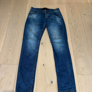 Blå jeans från Dolce & Gabbana - Snygga blå jeans från Dolce & Gabbana med klassisk femficksdesign och läderpatch på bakfickan. Jeansen har en lätt tvättad look med slitningar och raka ben. Perfekta för dig som gillar italiensk design och vill ha ett par stilrena jeans i garderoben.