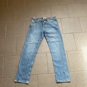 Blå jeans från Jack & Jones - Klassiska blå jeans från Jack & Jones med raka ben och normal passform. Jeansen har fem fickor, knappgylf och snygga kontrastsömmar. Tillverkade i slitstarkt denim med en tidlös look som funkar till allt. Perfekta för dig som gillar enkel och stilren stil. Det är modellen relaxed chris