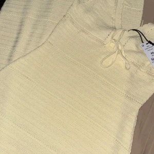  långklänning XS - Superfin stickad långklänning med v-ringning och knytband i midjan. Klänningen har ett snyggt virkat mönster och är ärmlös, perfekt för varma dagar. Ger en chill och trendig vibe till din look.