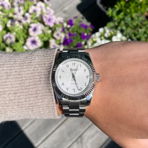 Seiko Mod med Arabisk urtavla  - Stilren Seiko Mod med silverfärgat armband i metall och klassisk rund urtavla. Urtavlan är vit med arabiska siffror och har en snygg räfflad kant runt boetten. Automatisk rörelse och robust länkarmband ger en lyxig känsla. Alla länkar+box tillkommer självklart vid köp‼️🙌