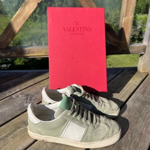 Valentino flycrew sneakers i mintgrön mocka - Snygga sneakers från Valentino Garavani i ljusgrön mocka med vita skinnpaneler och grön logga på plösen. Klassisk rund tå, platt sula och snörning. Perfekta för dig som gillar stilrena och exklusiva sneakers med en unik touch.