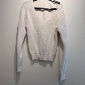 Vit stickad v-ringad tröja Zara - Mysig vit stickad tröja från Zara i storlek S. Tröjan har v-ringning, lång ärm och en lätt fluffig känsla. Perfekt för lager-på-lager och passar till både jeans och kjol. Enkel och stilren design som är lätt att matcha.