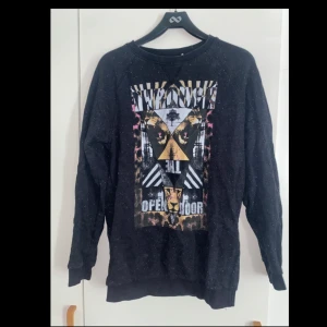 Svart sweatshirt från Vaillent PureX - Cool svart sweatshirt från Vaillent PureX med grafiskt tryck i vitt, gult och rosa framtill. Tröjan har lång ärm, rund hals och relaxed fit. 