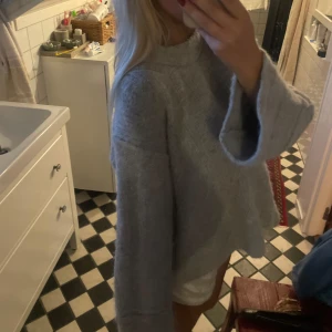 Grå oversized stickad tröja Dagmar - Supermjuk och oversized grå stickad tröja från Dagmar med vida ärmar och hög hals. Gjord i en lyxig mix av babyalpacka, ull och polyamid. Perfekt för dig som gillar chill och trendig stil med extra volym i ärmarna. Något nopprig men bra.